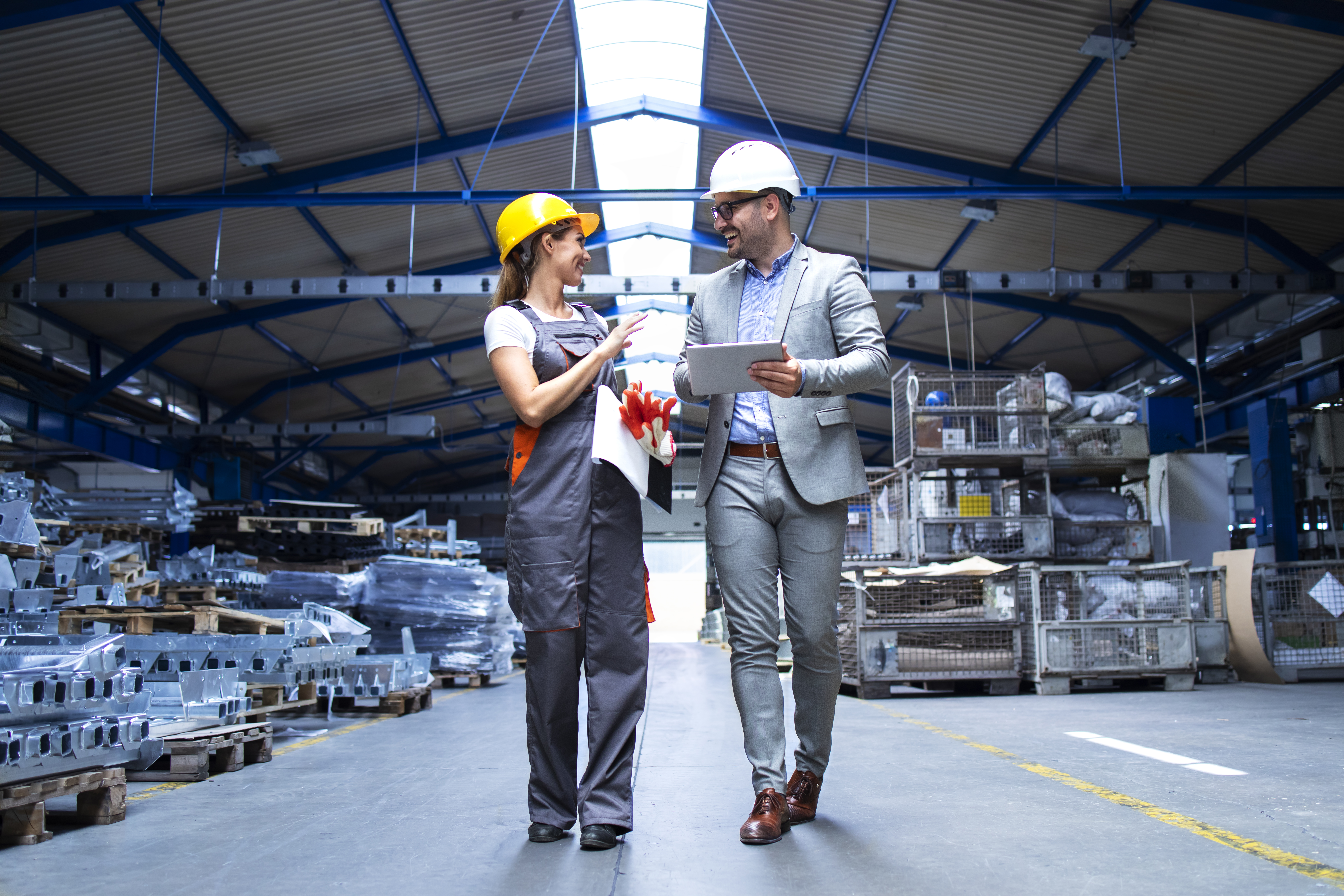 manager-supervisor-and-industrial-worker-in-uniform-walking-in-large-metal-factory-hall-and-talking-about-increasing-production.jpg