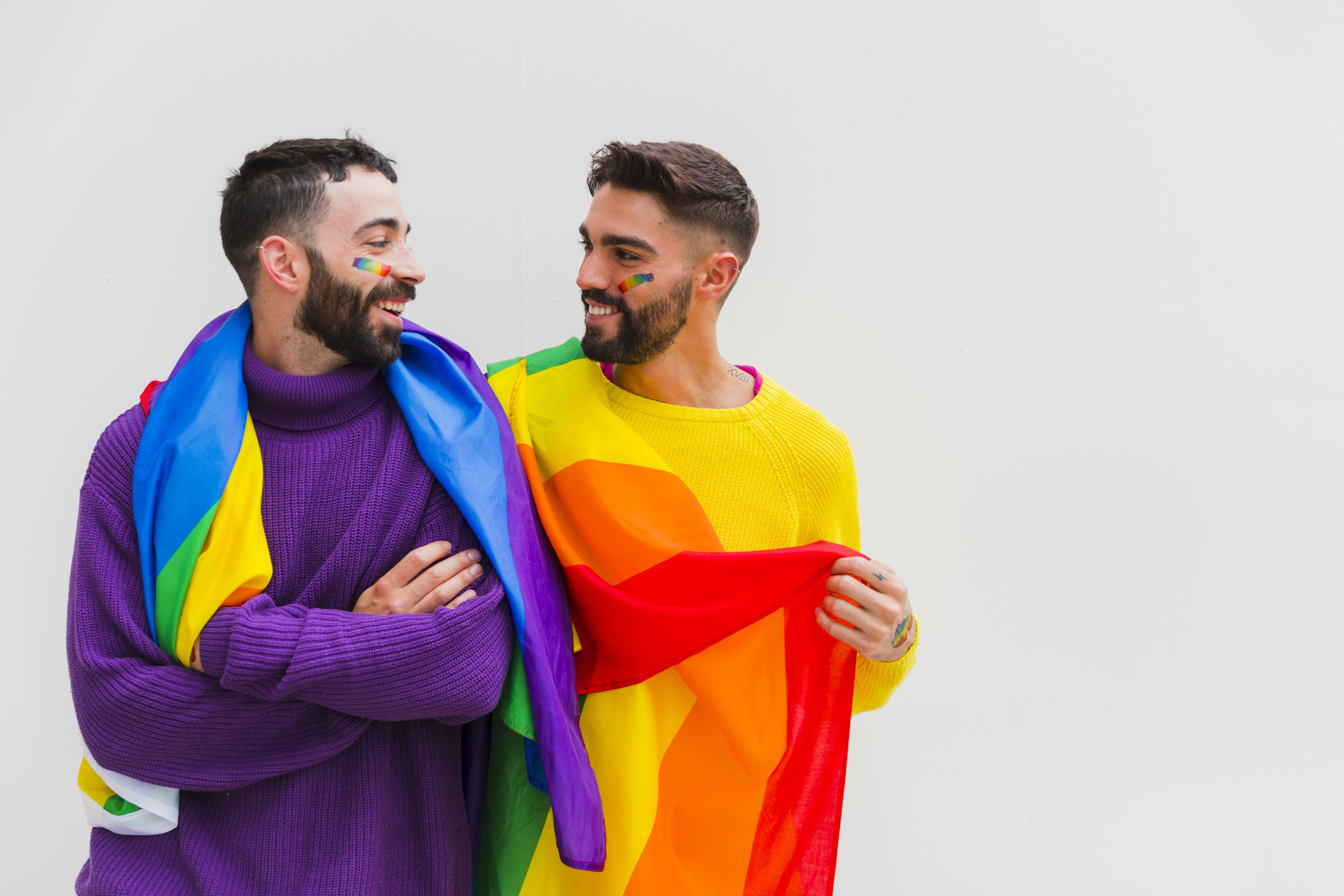 pareja-homosexual-con-banderas-lgbt-en-los-hombros-sonriendo-juntos.jpg